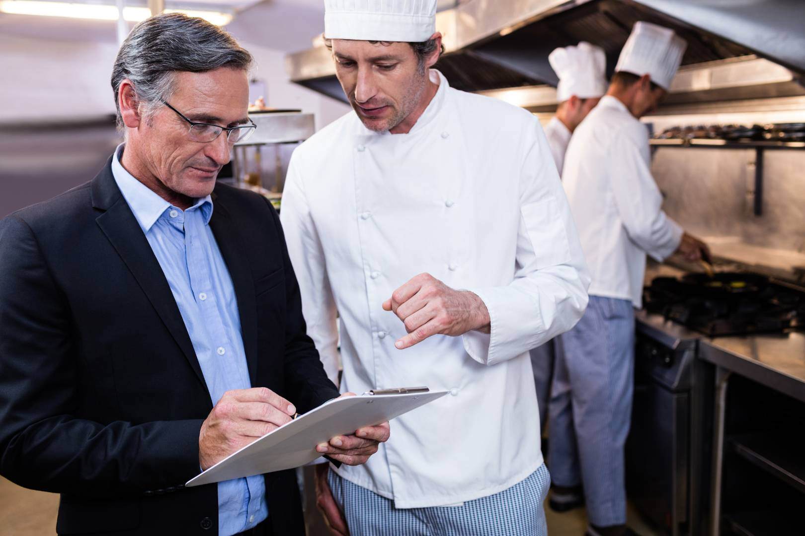 Manager and head chef review the daily log on a clipboard.